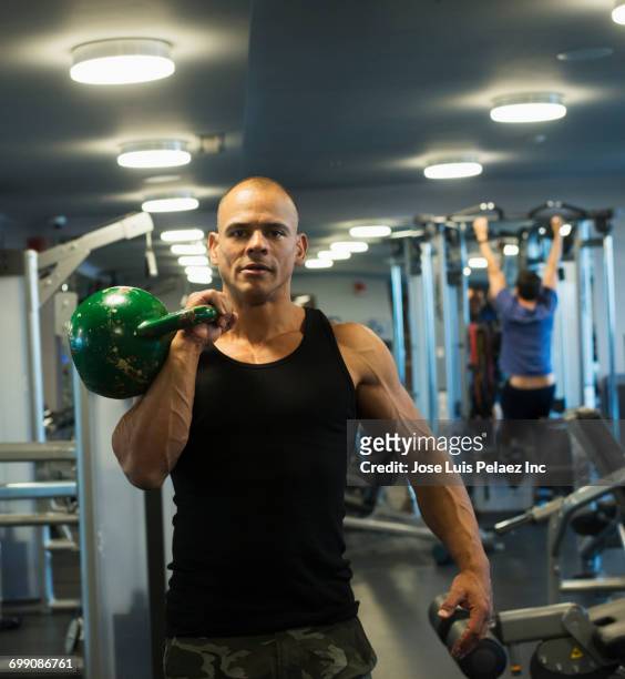hispanic man weightlifting with kettlebell in gymnasium - tank top stock pictures, royalty-free photos & images