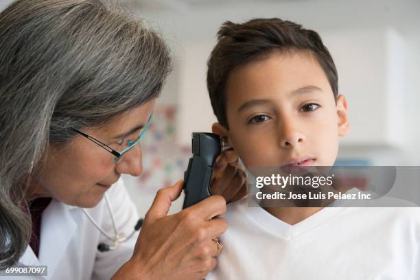 mixed race doctor checking ear of patient - otoscope stockfoto's en -beelden