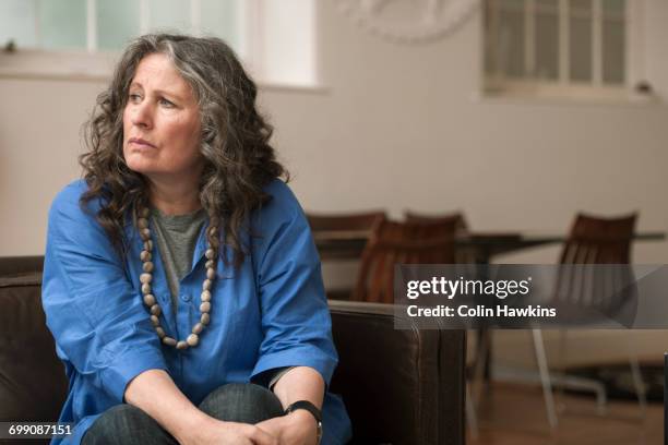 woman looking upset on couch - gray hair stress stock pictures, royalty-free photos & images