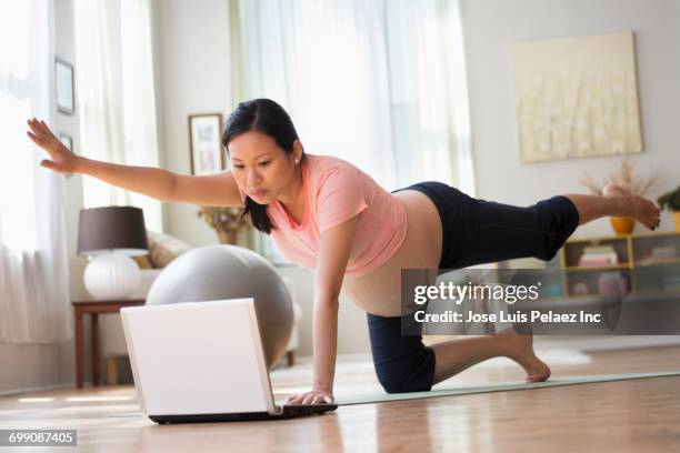 chinese expectant mother watching laptop performing yoga - one woman only videos stock pictures, royalty-free photos & images