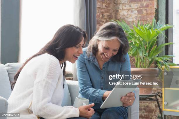 hispanic women reading digital tablet - mother happy reading tablet stock pictures, royalty-free photos & images