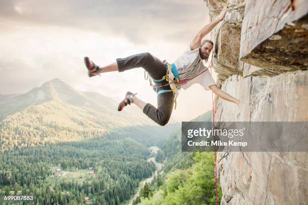 caucasian man hanging from rock while climbing - draped fotografías e imágenes de stock