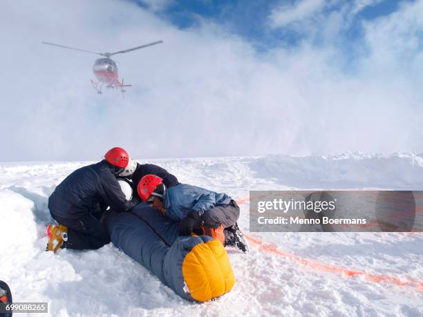 mountain rescuers are protecting a victim for the down wind of the landing helicopter at 14.000 foot on denali, formerly known as mount mckinley.  - helicopter rescue stock pictures, royalty-free photos & images