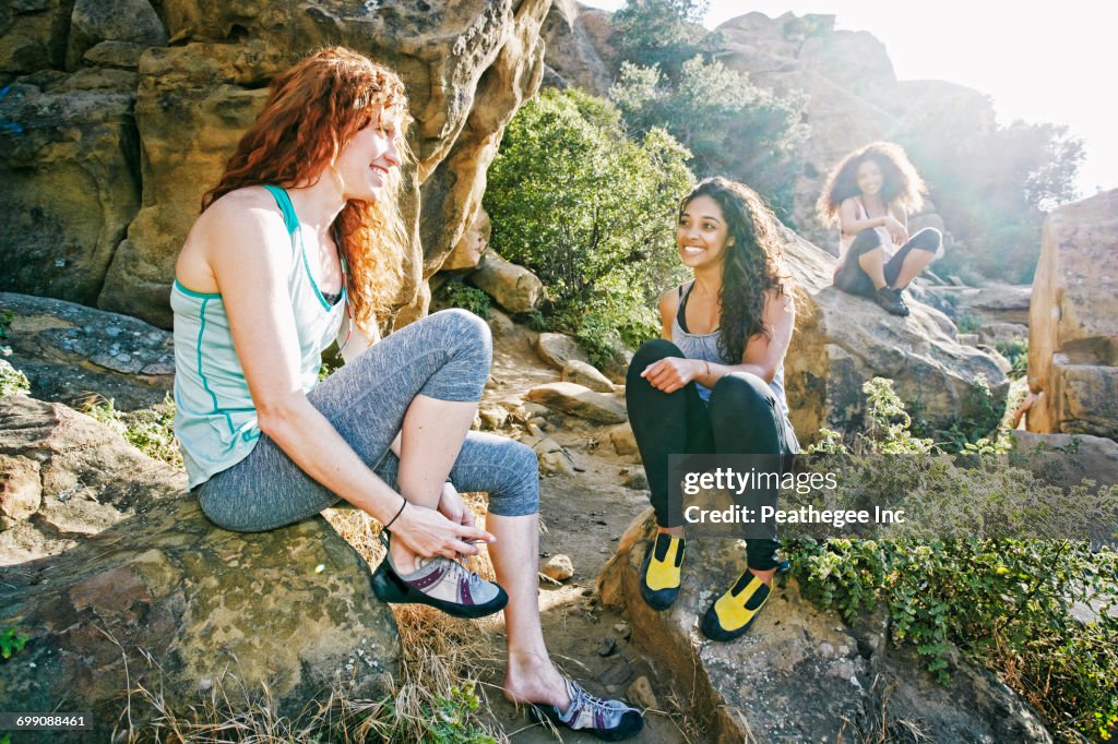 Smiling women sitting on rocks preparing for rock climbing