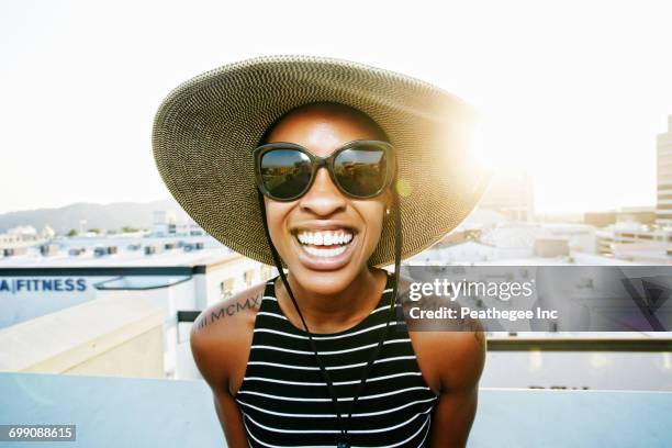 black woman wearing sun hat and sunglasses on rooftop - tattoo shoulder stock pictures, royalty-free photos & images