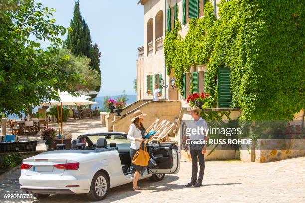 porter welcoming couple arriving in convertible to boutique hotel, majorca, spain - car arrival stock pictures, royalty-free photos & images