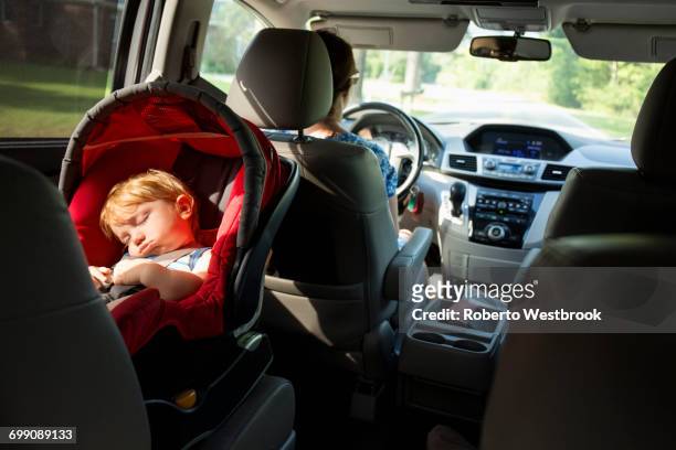 caucasian mother driving car with baby son in car seat - sleeping in car stockfoto's en -beelden