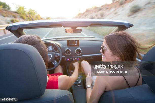 rear view of two young women driving on rural road in convertible, majorca, spain - car rental stock pictures, royalty-free photos & images