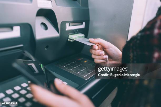 hand of young woman inserting credit card into cash machine - atm stock pictures, royalty-free photos & images