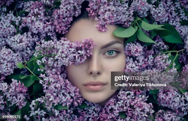 face of caucasian woman surrounded by purple flowers - entourer photos et images de collection