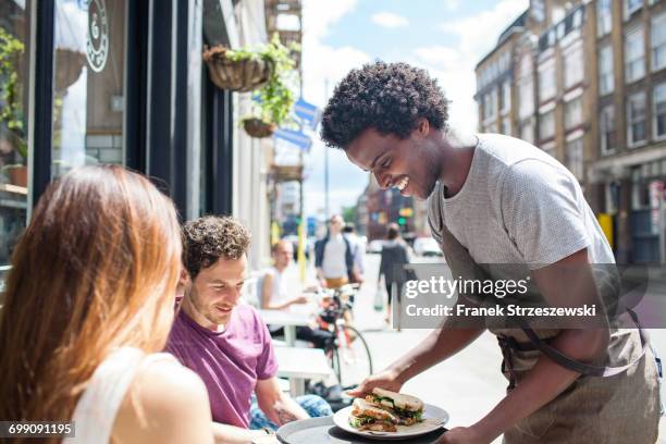 waiter serving lunch to couple at city sidewalk cafe - coppie cibo food bistrot foto e immagini stock