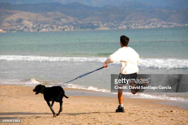 young boy running along the beach of san juan in alicante - boy running with dog stock-fotos und bilder