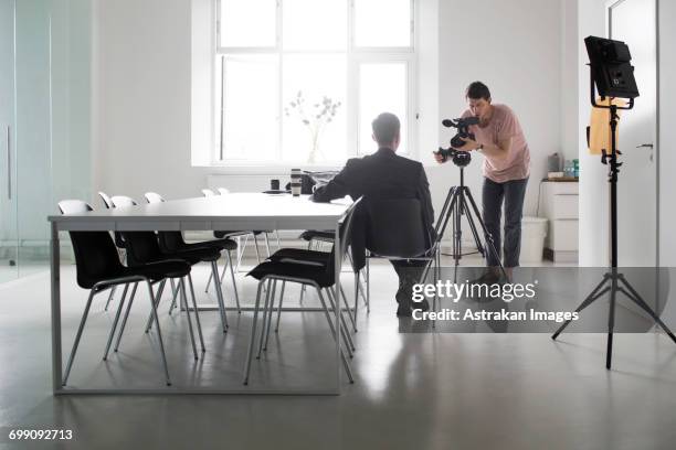 photographer recording interview of businessman in board room - shooting fotografías e imágenes de stock