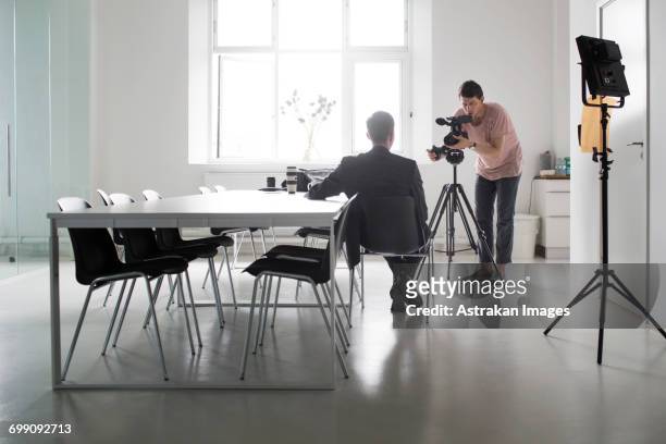 photographer recording interview of businessman in board room - filming stock pictures, royalty-free photos & images