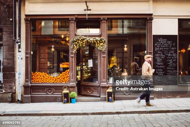 sweden, stockholm, gamla stan, man walking by cafe - street cafe stockfoto's en -beelden
