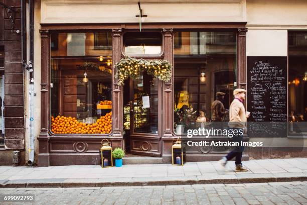 sweden, stockholm, gamla stan, man walking by cafe - stockholm street stock pictures, royalty-free photos & images