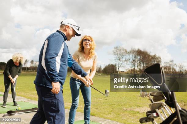 happy friends practicing golf at driving range on sunny day - driving range stock pictures, royalty-free photos & images