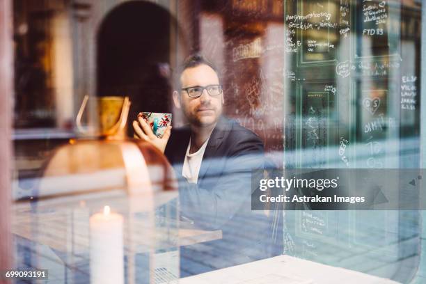 sweden, stockholm, gamla stan, man relaxing in cafe seen through window - fika stock pictures, royalty-free photos & images