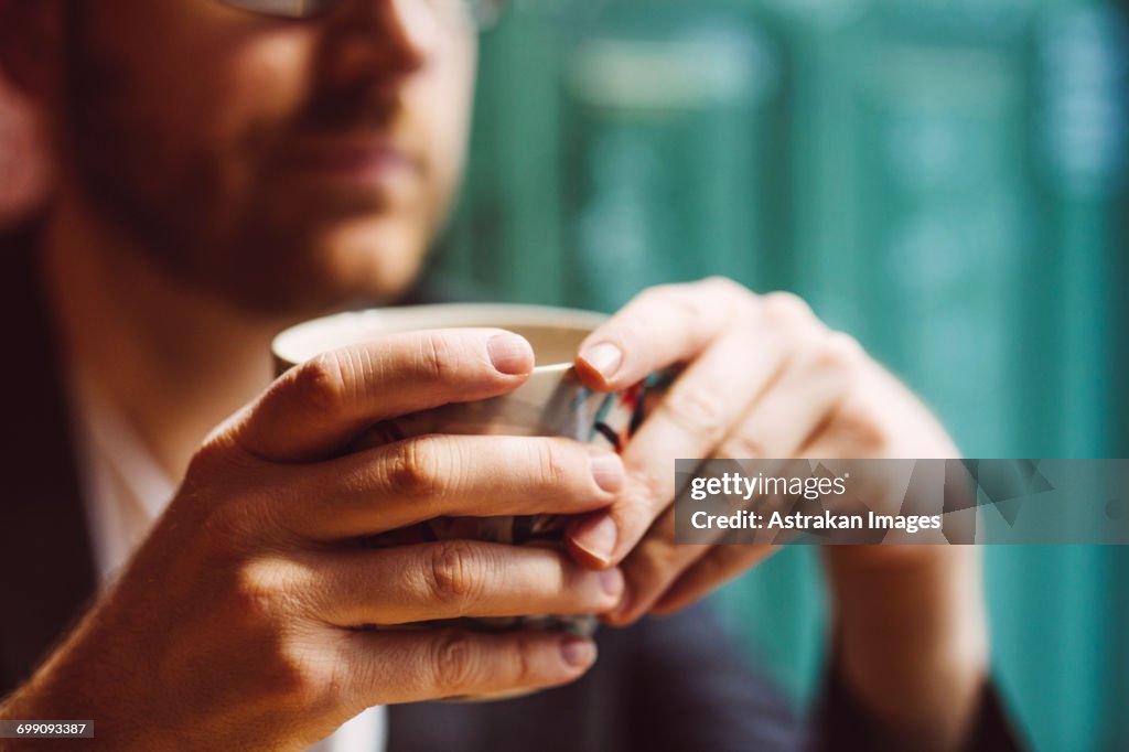 Sweden, Stockholm, Gamla Stan, Man holding coffee cup in cafe, close up of hands