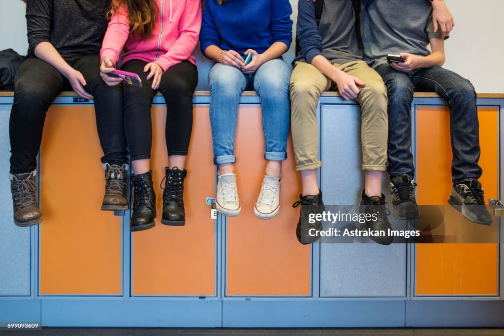 Low section of schoolchildren (12-13) sitting on lockers
