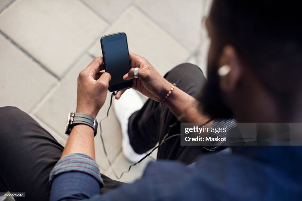 High angle view of man surfing the net on mobile phone