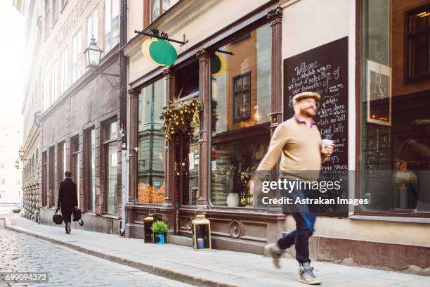 sweden, stockholm, gamla stan, man walking by cafe - stockholm old town fotografías e imágenes de stock