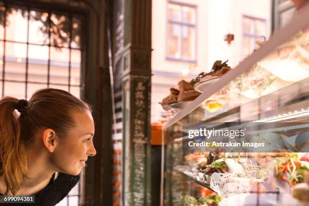 sweden, stockholm, gamla stan, smiling woman looking at display in cafe - fika stock pictures, royalty-free photos & images