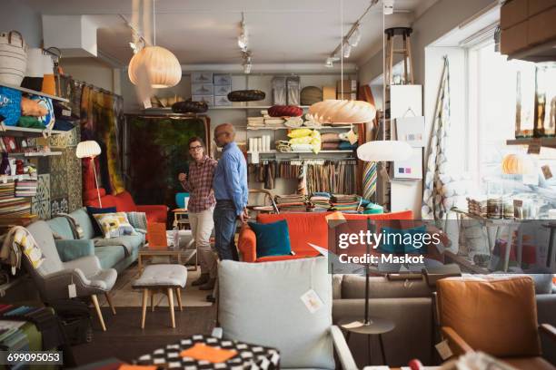 owner showing furniture to customer at store - möbelgeschäft stock-fotos und bilder