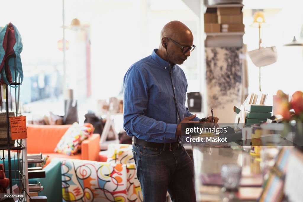 Senior Customer Writing Notes While Using Technology In Store High-Res ...