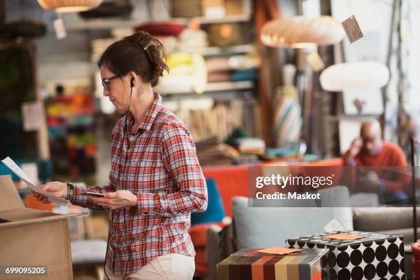 owner listening music through phone while reading document at store - checked shirt stock pictures, royalty-free photos & images