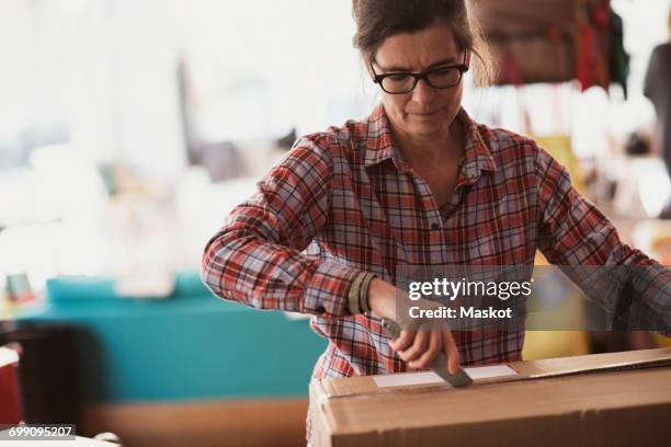 female owner unpacking box with utility knife at store - utility knife stock-fotos und bilder