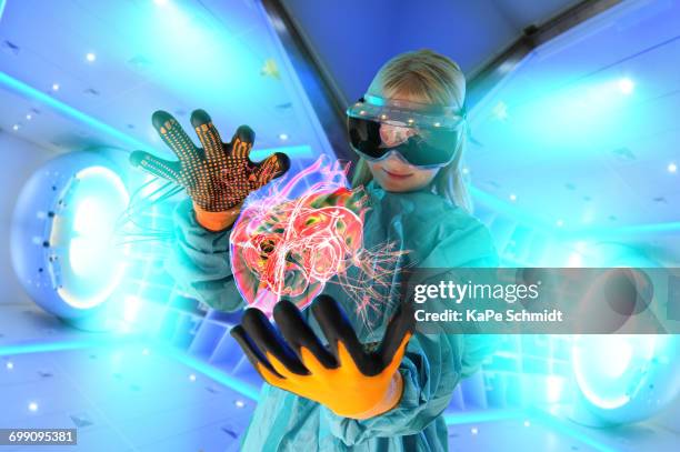 girl in virtual reality headset interacting with digital floating human heart - helen schmidt stockfoto's en -beelden