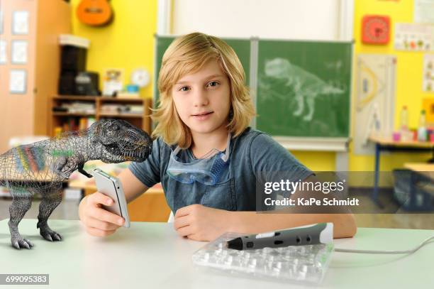 portrait of boy with hand held computer and 3d model of tyrannosaurus rex - top prospects game stockfoto's en -beelden