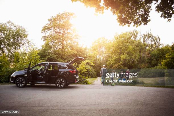 open black electric car with family walking in park - car scandinavia stock pictures, royalty-free photos & images