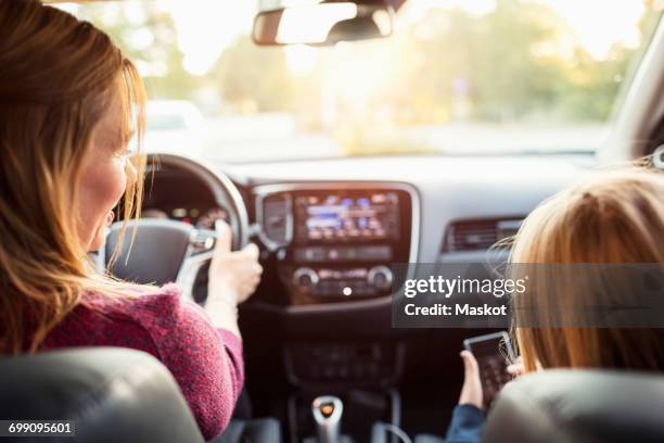 rear view of woman and girl sitting in electric car - daughter car stock pictures, royalty-free photos & images