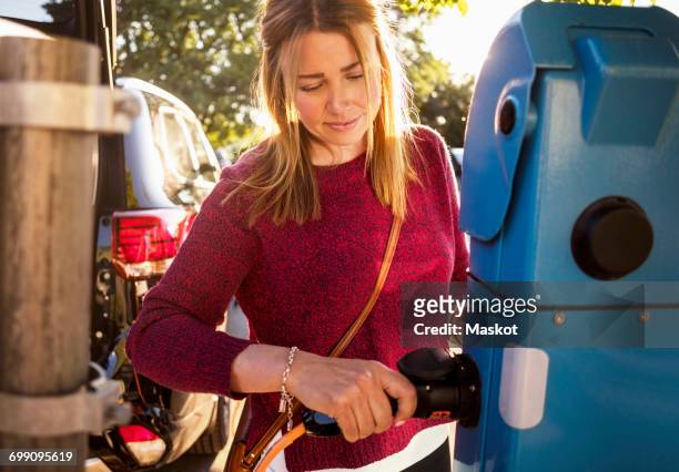 mature woman plugging cable at station - red car wire stock pictures, royalty-free photos & images