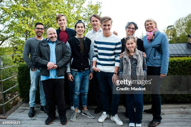 portrait of happy multi-ethnic friends and family standing against hedge in yard - fugitive stock pictures, royalty-free photos & images