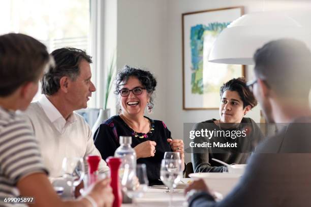 happy friends discussing at dining table in dinner party - family reunion stock pictures, royalty-free photos & images