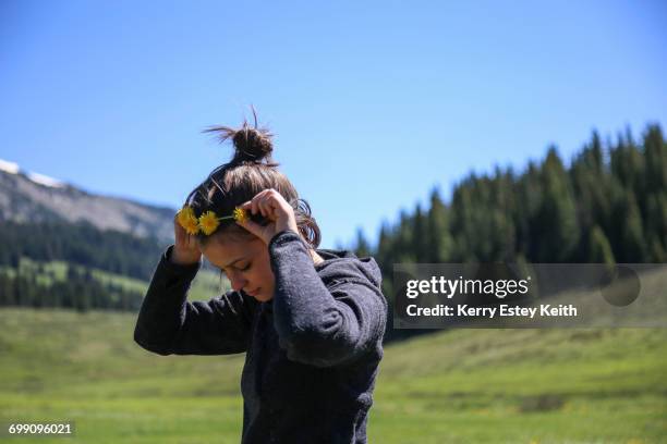 teenage girl puts flower crown in her hair while walking in a high mountain meadow. - kerry estey keith - fotografias e filmes do acervo