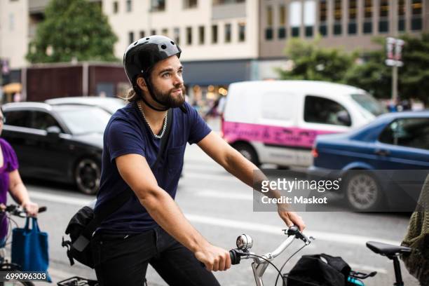 thoughtful man riding bicycle in traffic on city street - file stockfoto's en -beelden