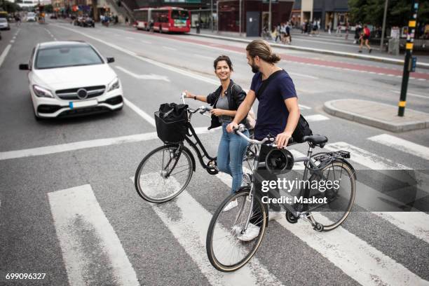 smiling friends with bicycles crossing city street - zebrastreifen stock-fotos und bilder