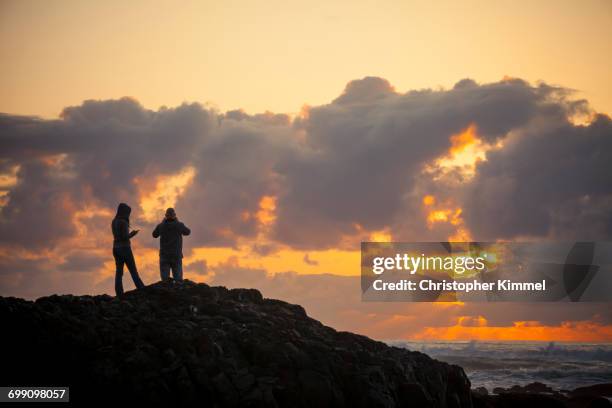 a young couple enjoys the sunset from lincoln beach, oregon. - lincoln city oregon stock pictures, royalty-free photos & images