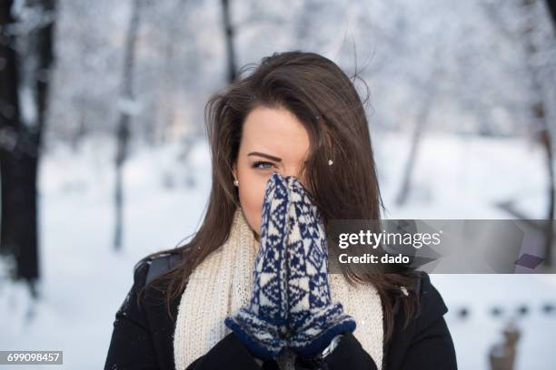 woman wearing mittens holding her hands in front of her face - woman hands in mittens stock-fotos und bilder