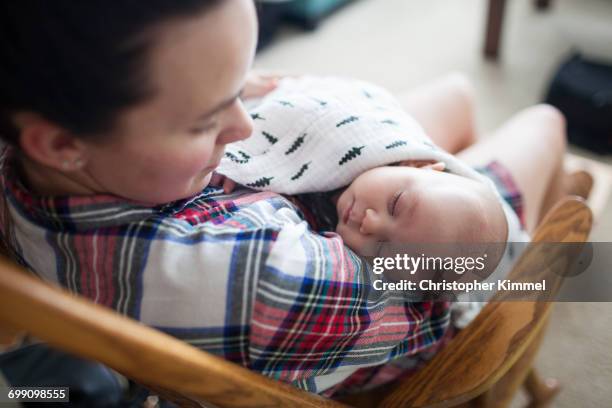 a young mother rocks her baby boy to sleep. - surrey british columbia stock pictures, royalty-free photos & images