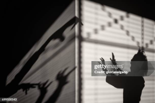 silhouette of a scared girl with shadow monsters - schattenspielfigur stock-fotos und bilder