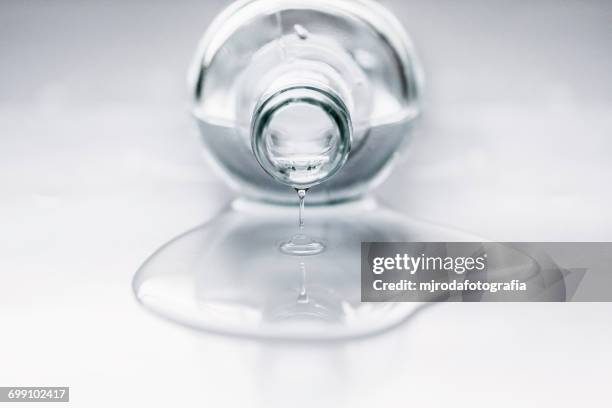 bottle lying on table with water coming out - knoeien stockfoto's en -beelden