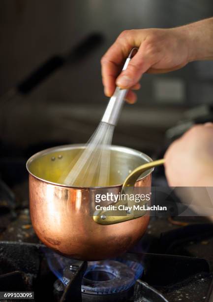 close-up of chef whisking food in a pot, piedmont, italy - schneebesen stock-fotos und bilder