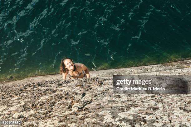 high angle view of smiling young woman looking up on a rock ledge - killarney lake stock pictures, royalty-free photos & images