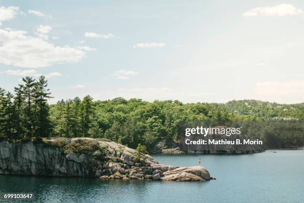 distant view of young woman standing on a rock in the middle of george lake - killarney lake stock pictures, royalty-free photos & images