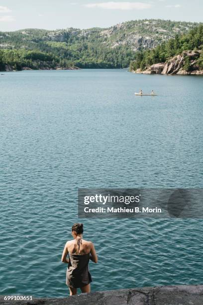 young woman wrapped in towel while a canoe is crossing the lake - killarney lake stock pictures, royalty-free photos & images